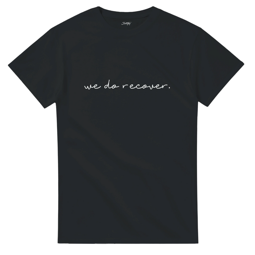 Black T-shirt with white handwritten text that reads “we do recover.” symbolizing strength, healing, and hope in the recovery journey